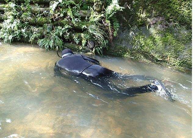 川に沈んでいる木材の周辺を潜水して確認している様子